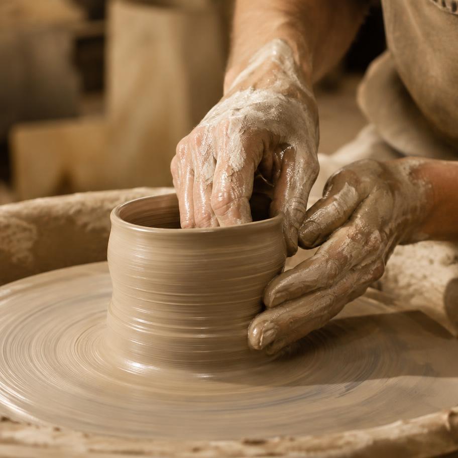 Hands shaping clay on a pottery wheel